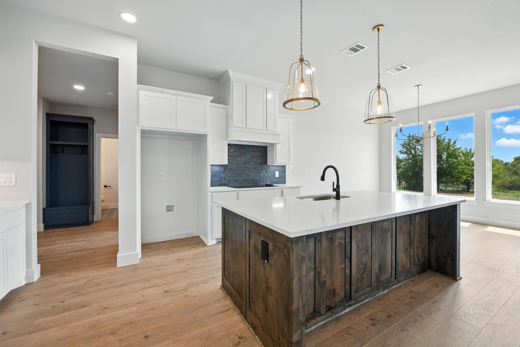 Kitchen with stained wood hood, white island, and pendant lighting in an Abba River Homes build.