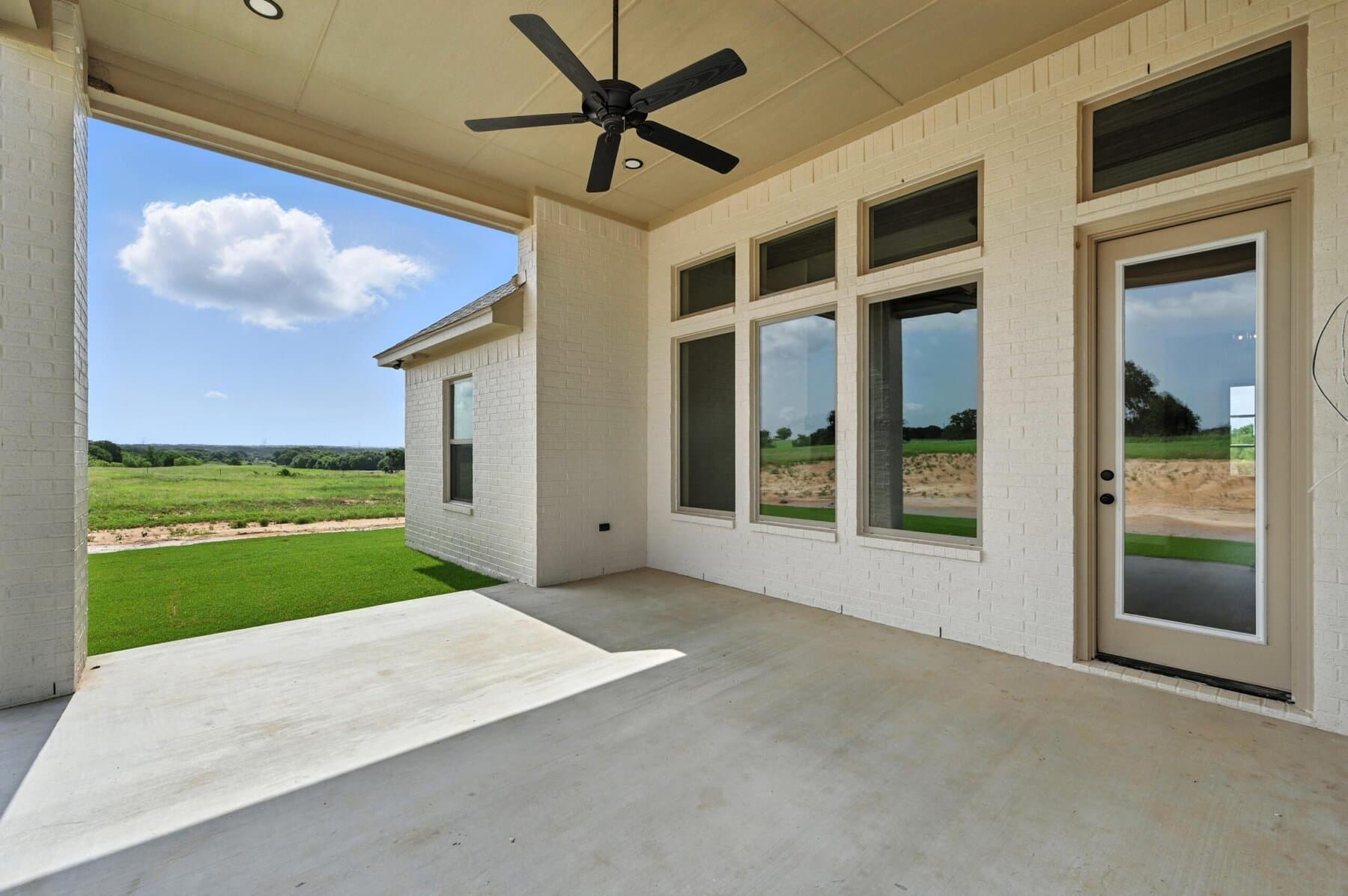 Covered porch with ceiling fan and open land view in an Abba River Homes build.