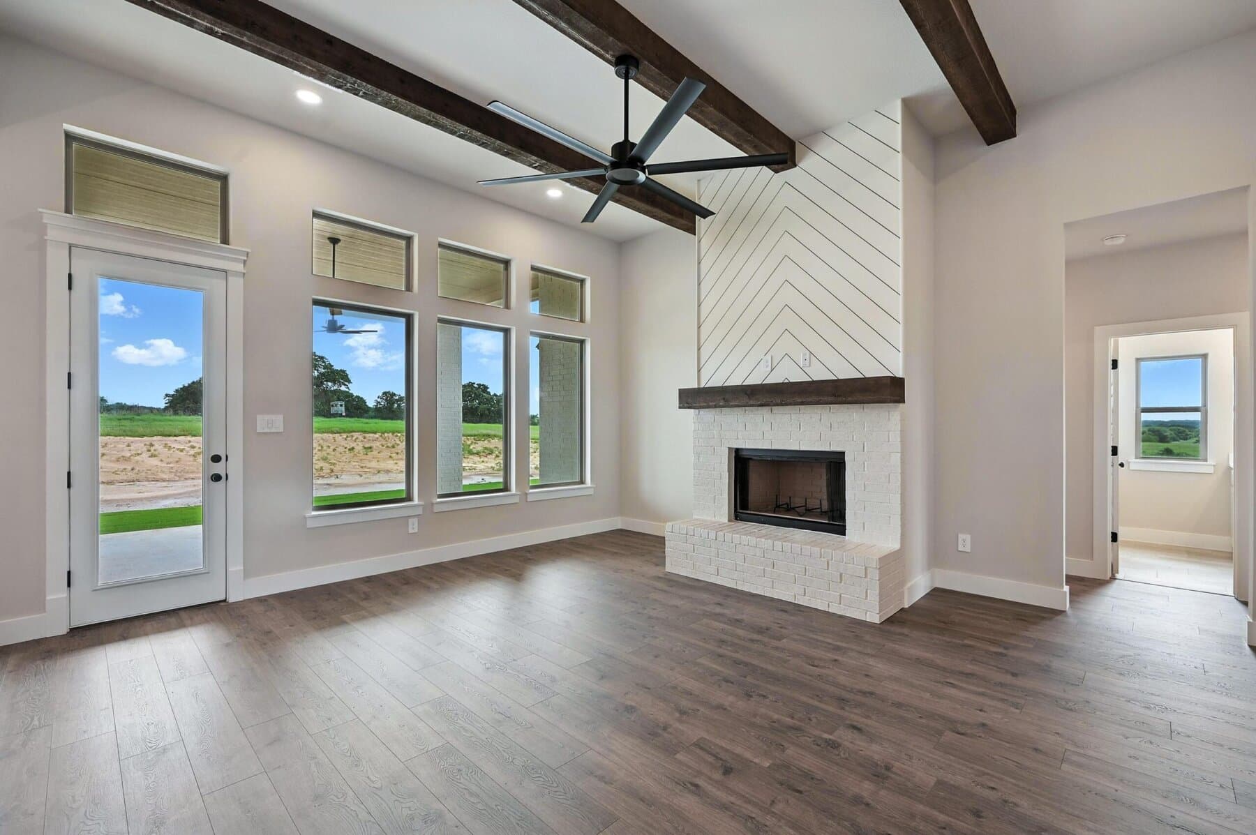 Living room with fireplace, beams, and tall windows in an Abba River Homes build.