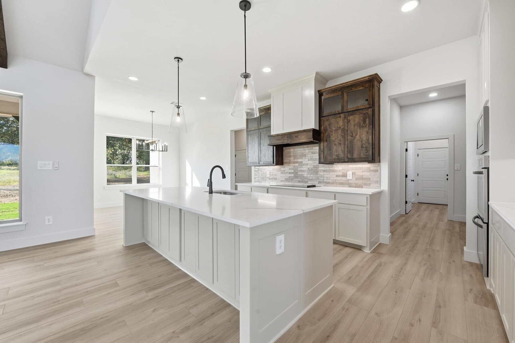 Bright kitchen island with pendant lights and outdoor view in an Abba River Homes build.