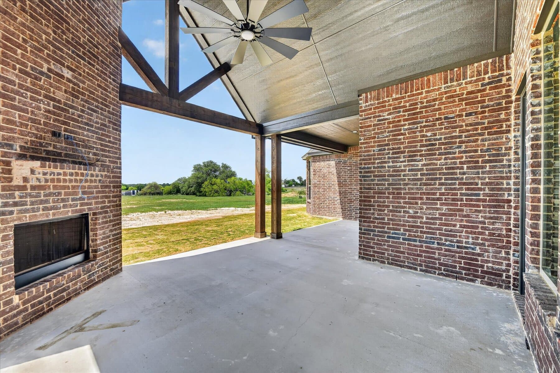 Covered Abba River Homes porch with outdoor fireplace and open Parker County view.