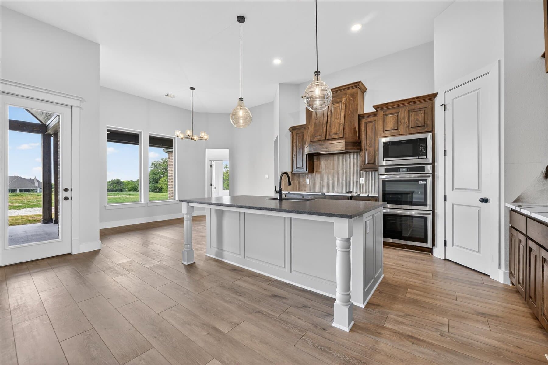 White kitchen with island, pendant lighting, and wood range detail in an Abba River Homes build.