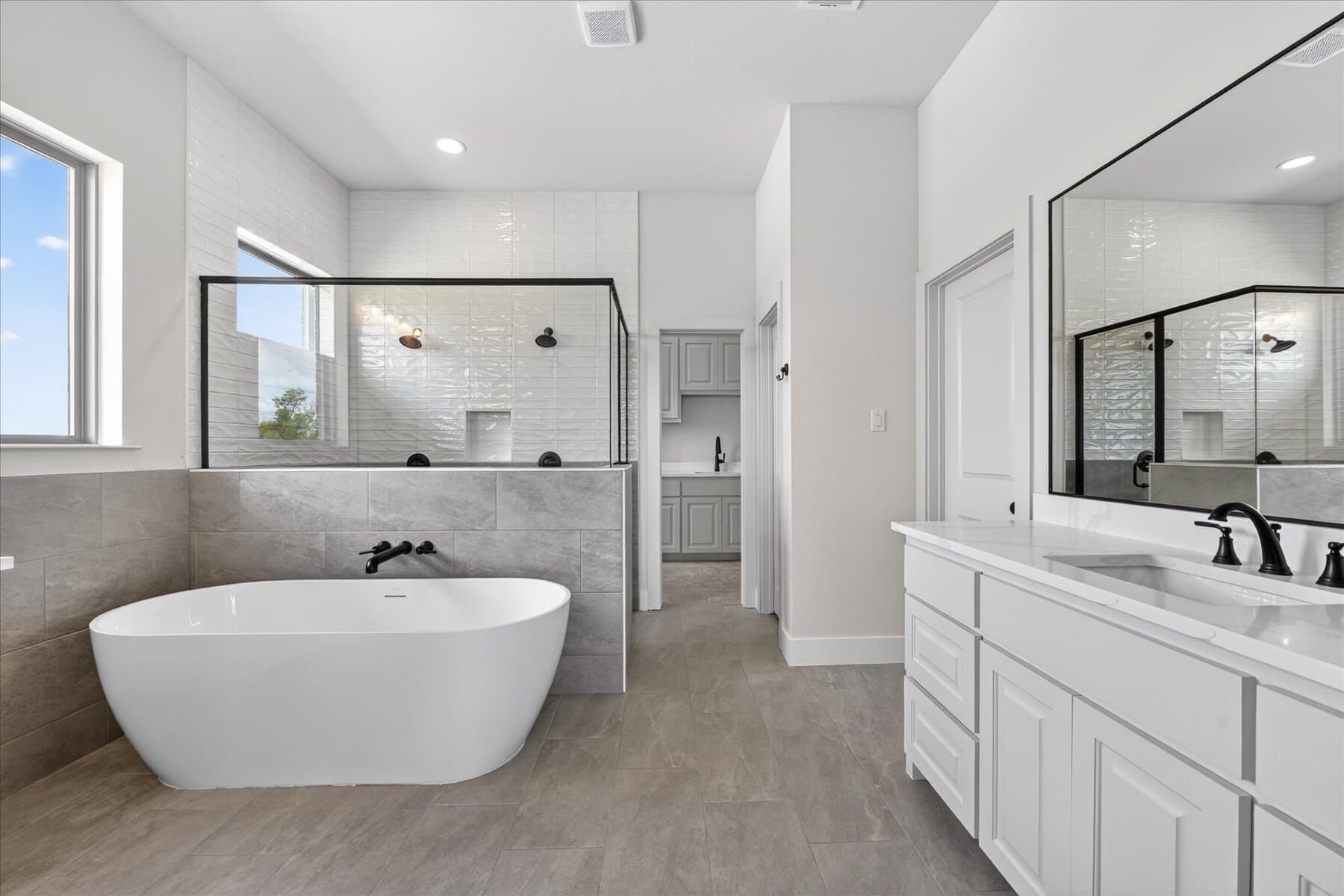 Primary bath with freestanding tub, dual vanity, and glass shower in an Abba River Homes build.
